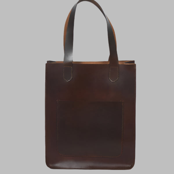 A brown leather shopper bag with a structured design and a front pocket, displayed against a plain background.
