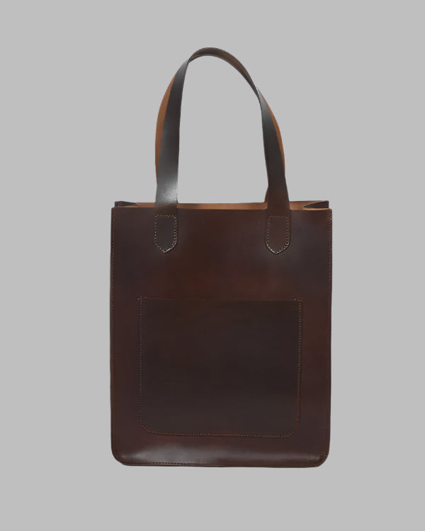 A brown leather shopper bag with a structured design and a front pocket, displayed against a plain background.