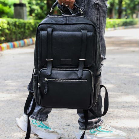 A person wearing a black leather backpack with a stylish design, featuring multiple compartments and a rich black color.