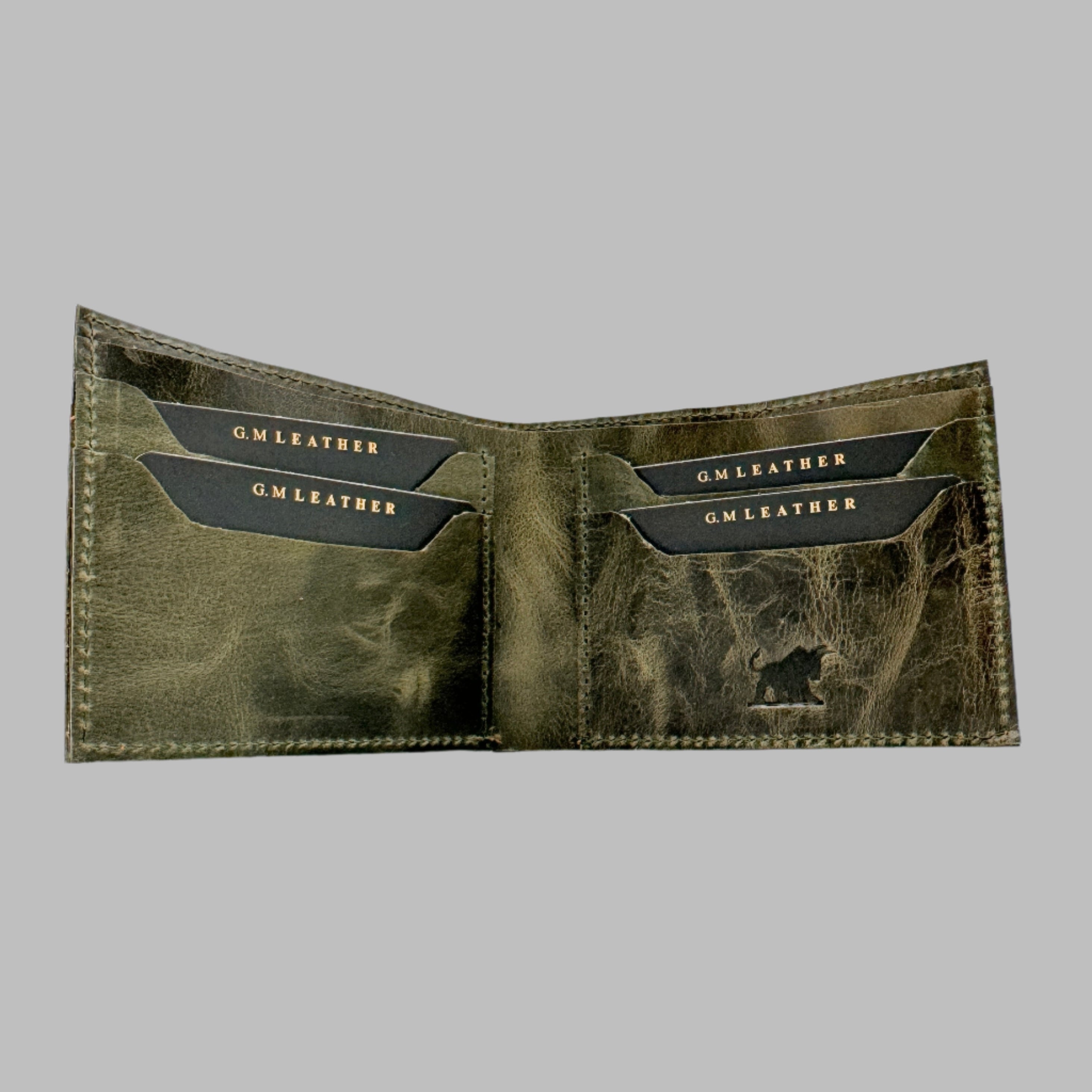 A green and brown leather wallet with upper stitch detailing, displayed in front of its black box packaging with a logo.