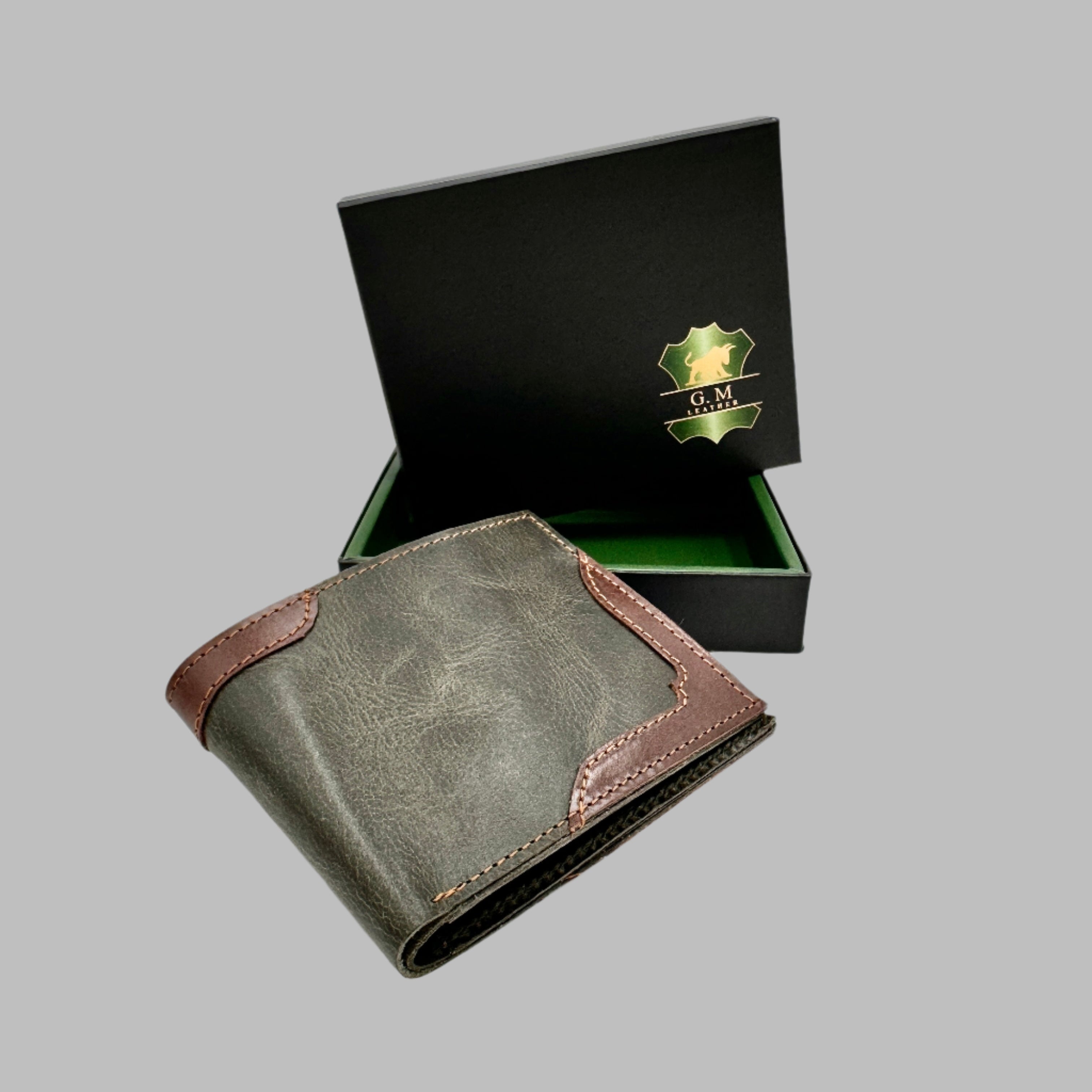 A green and brown leather wallet with upper stitch detailing, displayed in front of its black box packaging with a logo.