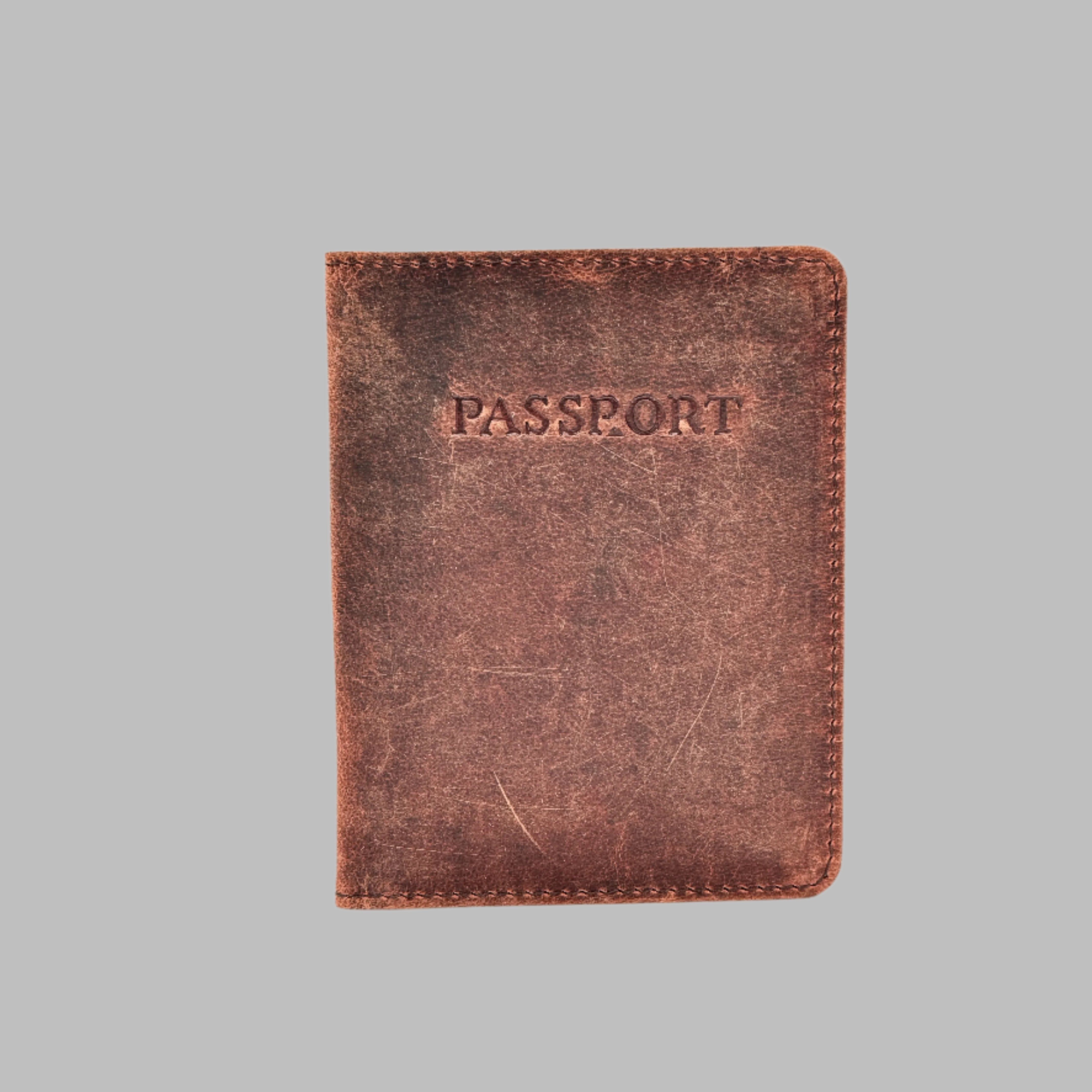 A brown genuine leather passport cover with the word 'PASSPORT' embossed on the front. It includes a card holder slot.