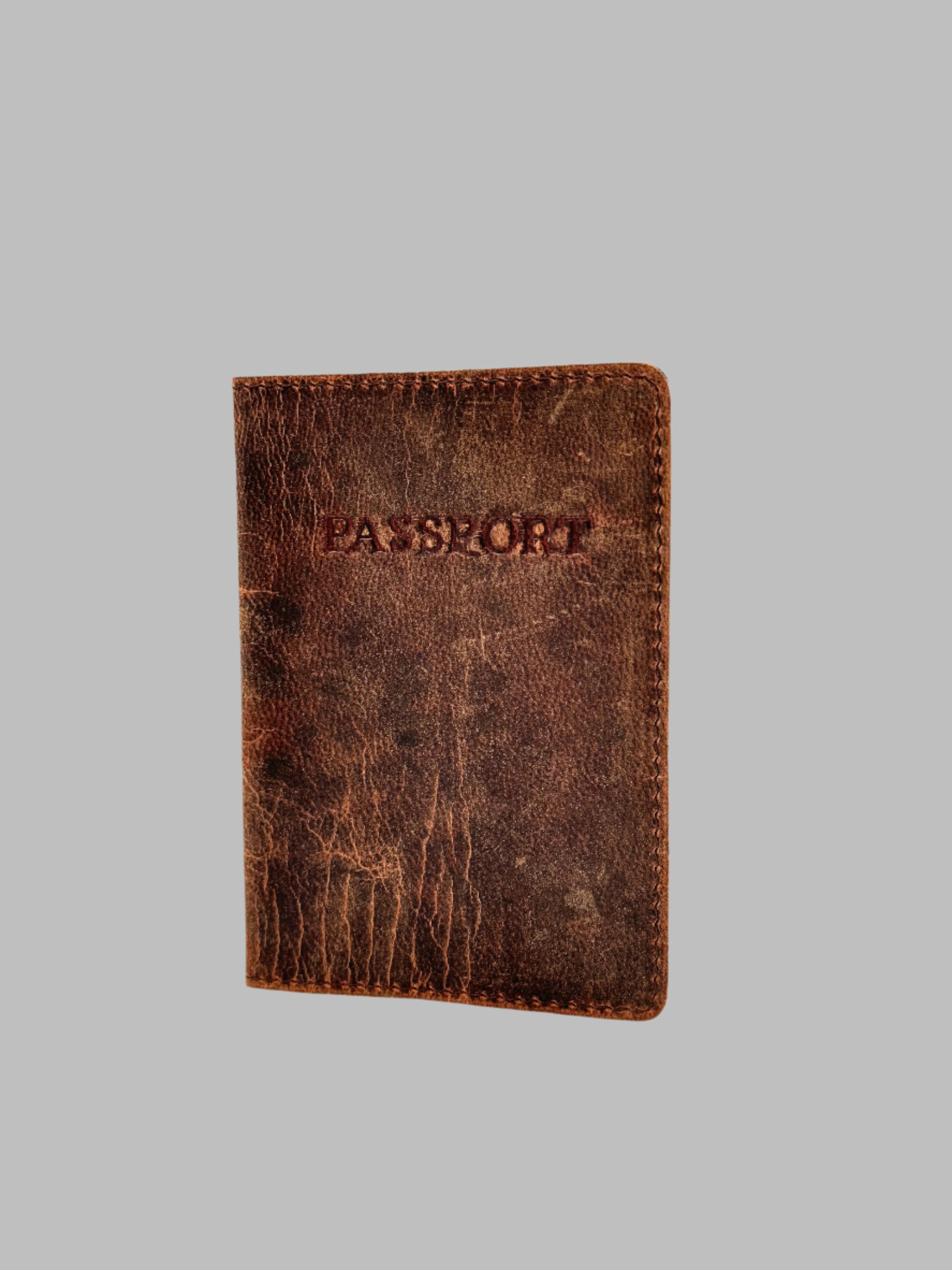 A brown leather passport cover with the word 'PASSPORT' embossed on the front.
