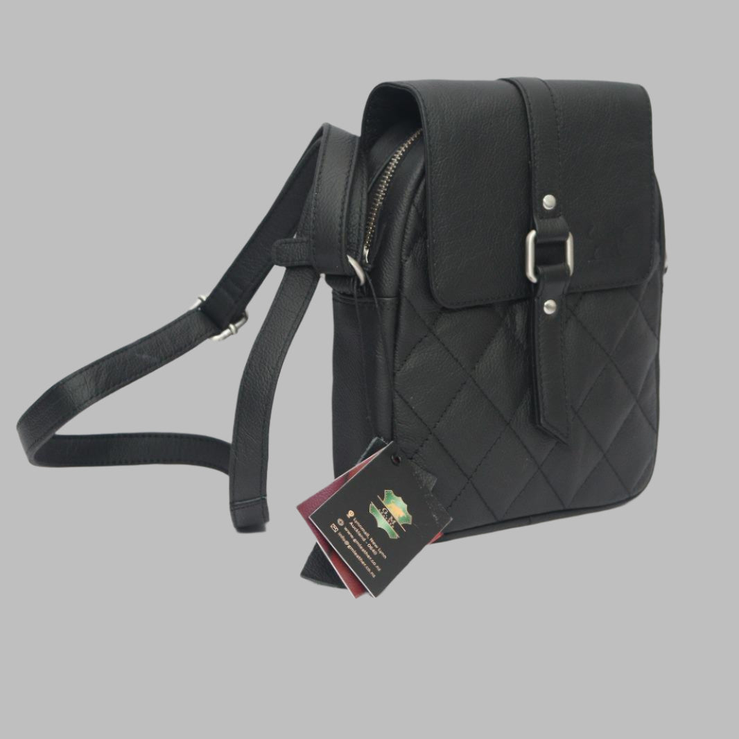 Black leather sling bag with a quilted design, a buckle closure, and an adjustable strap, displayed with a price tag.