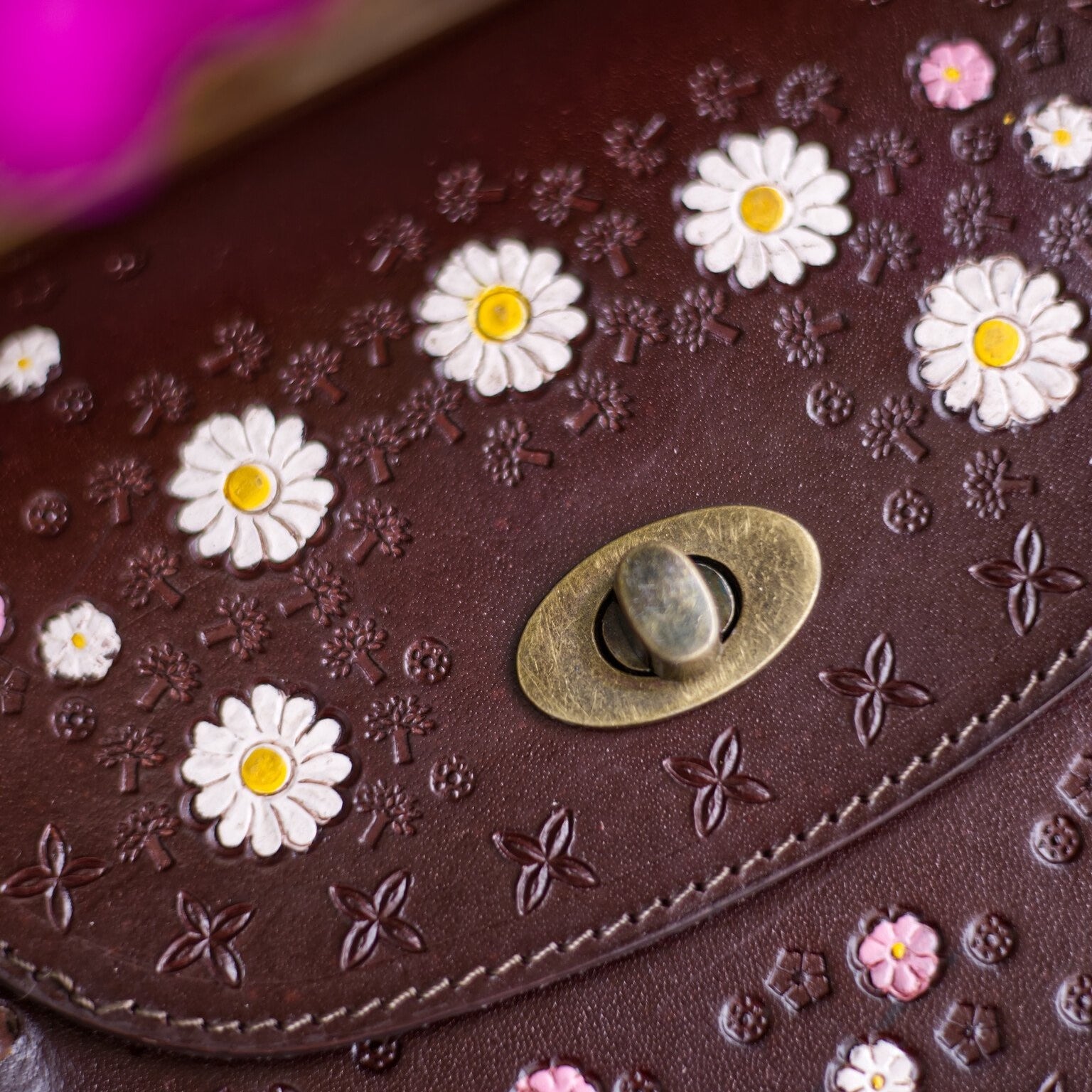 Brown leather bag with floral patterns and a decorative button.