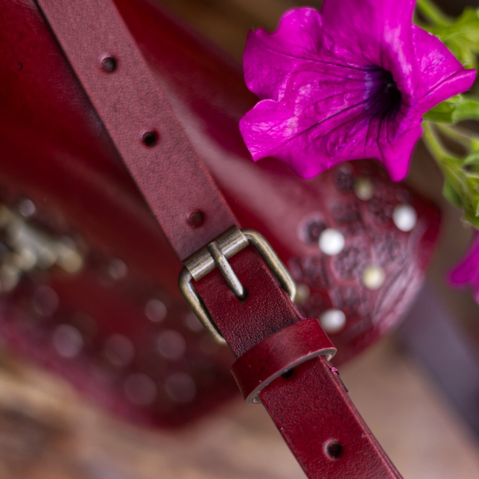 Close-up of a red leather strap with a pink flower on a blurred background