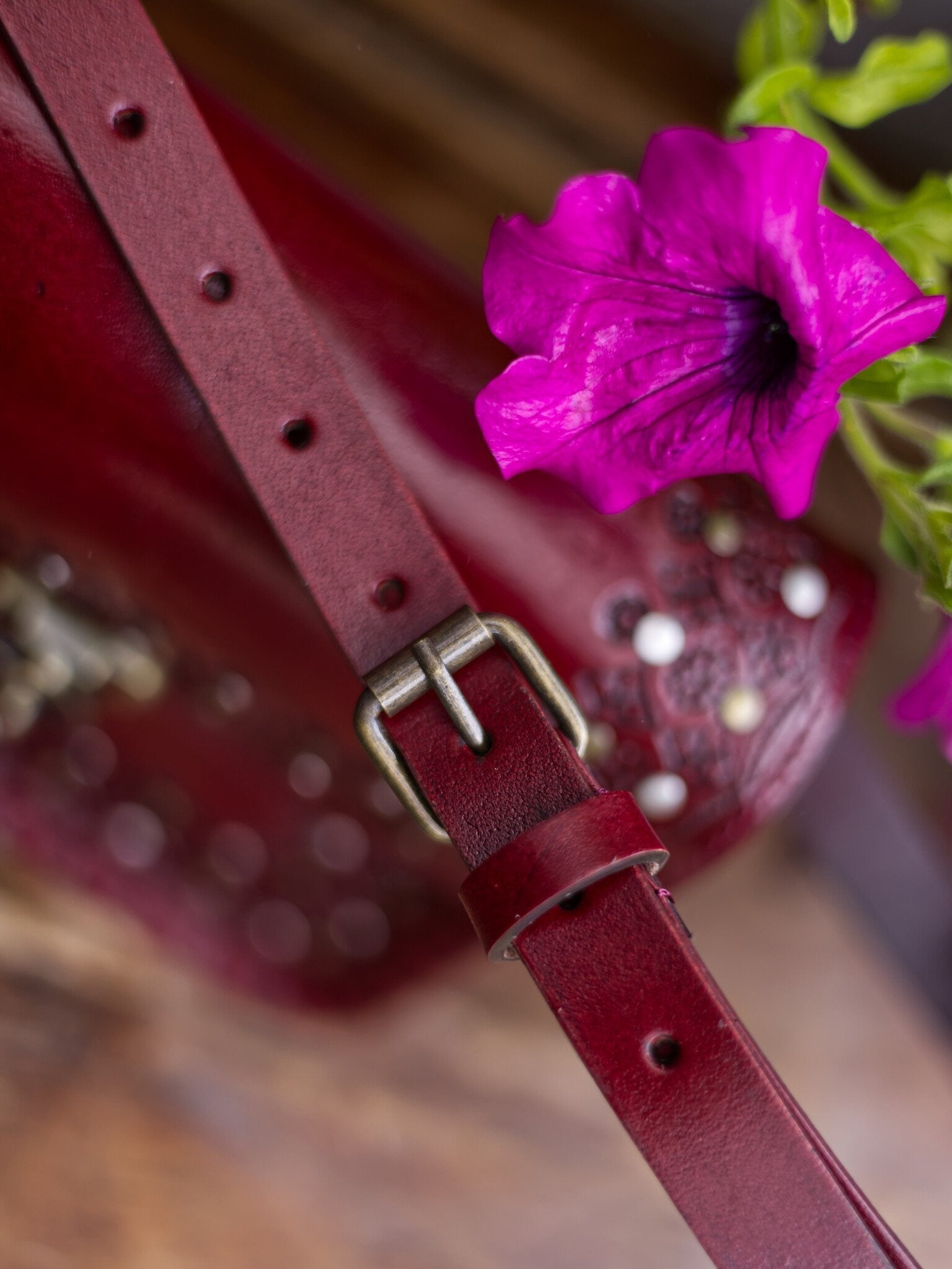 Close-up of a red leather strap with a pink flower on a blurred background