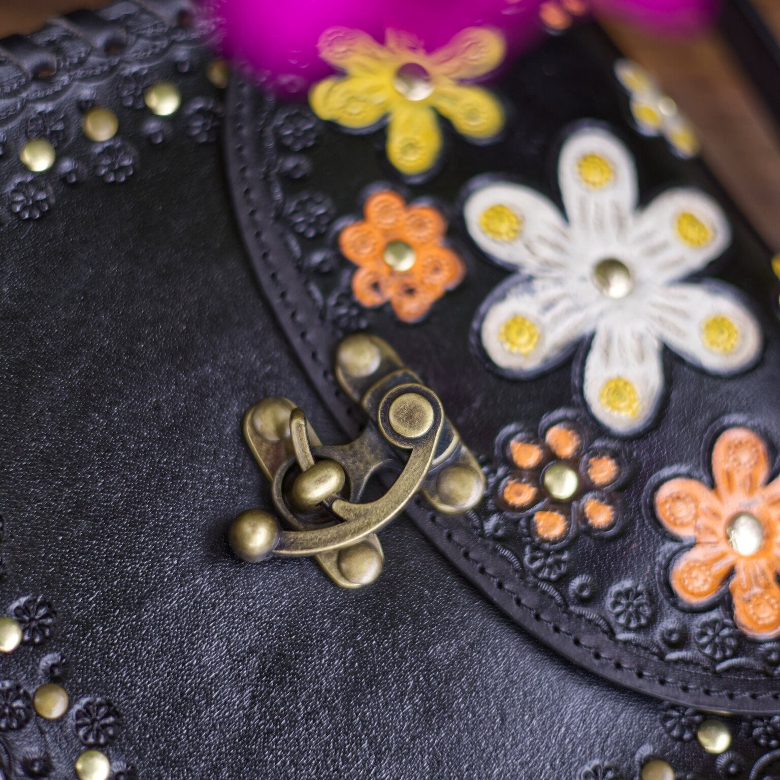 Black leather clutch with floral embellishments and a gold clasp.