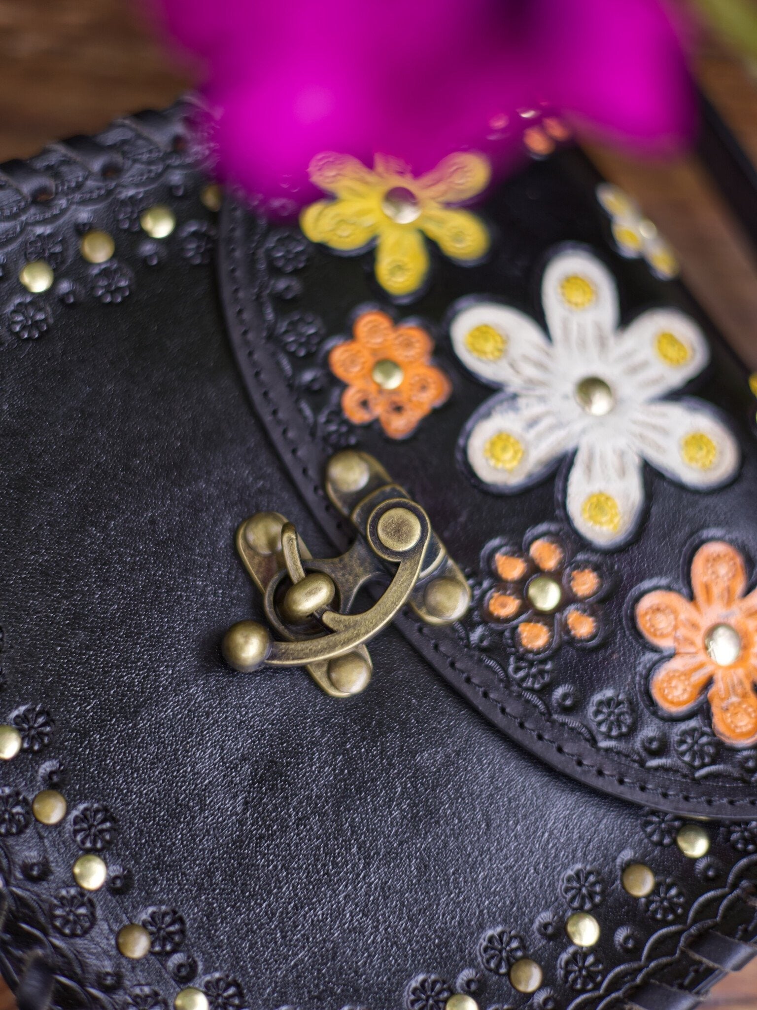 Black leather clutch with floral embellishments and a gold clasp.