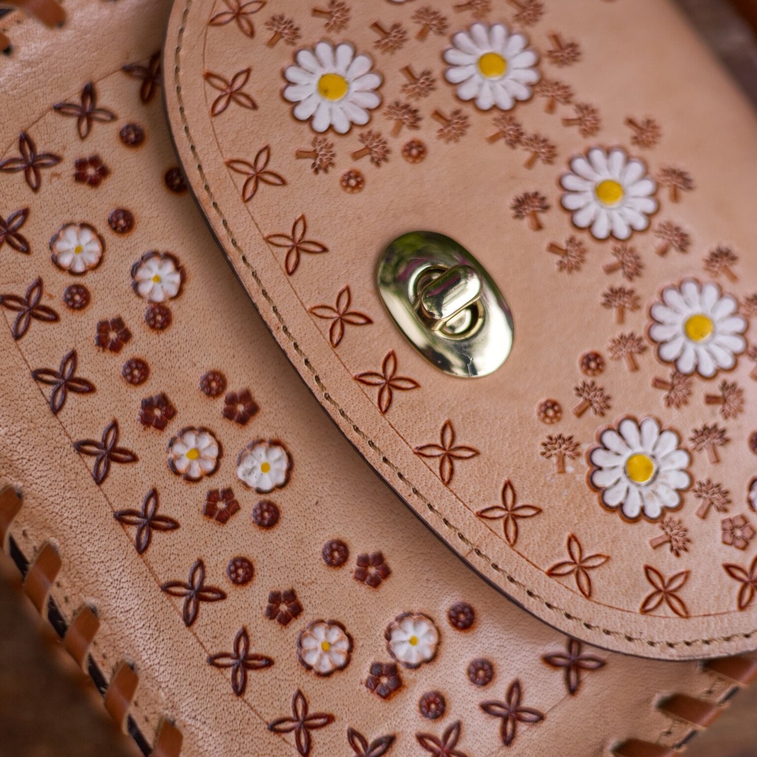 Close-up of a leather handbag with floral patterns and a gold clasp.