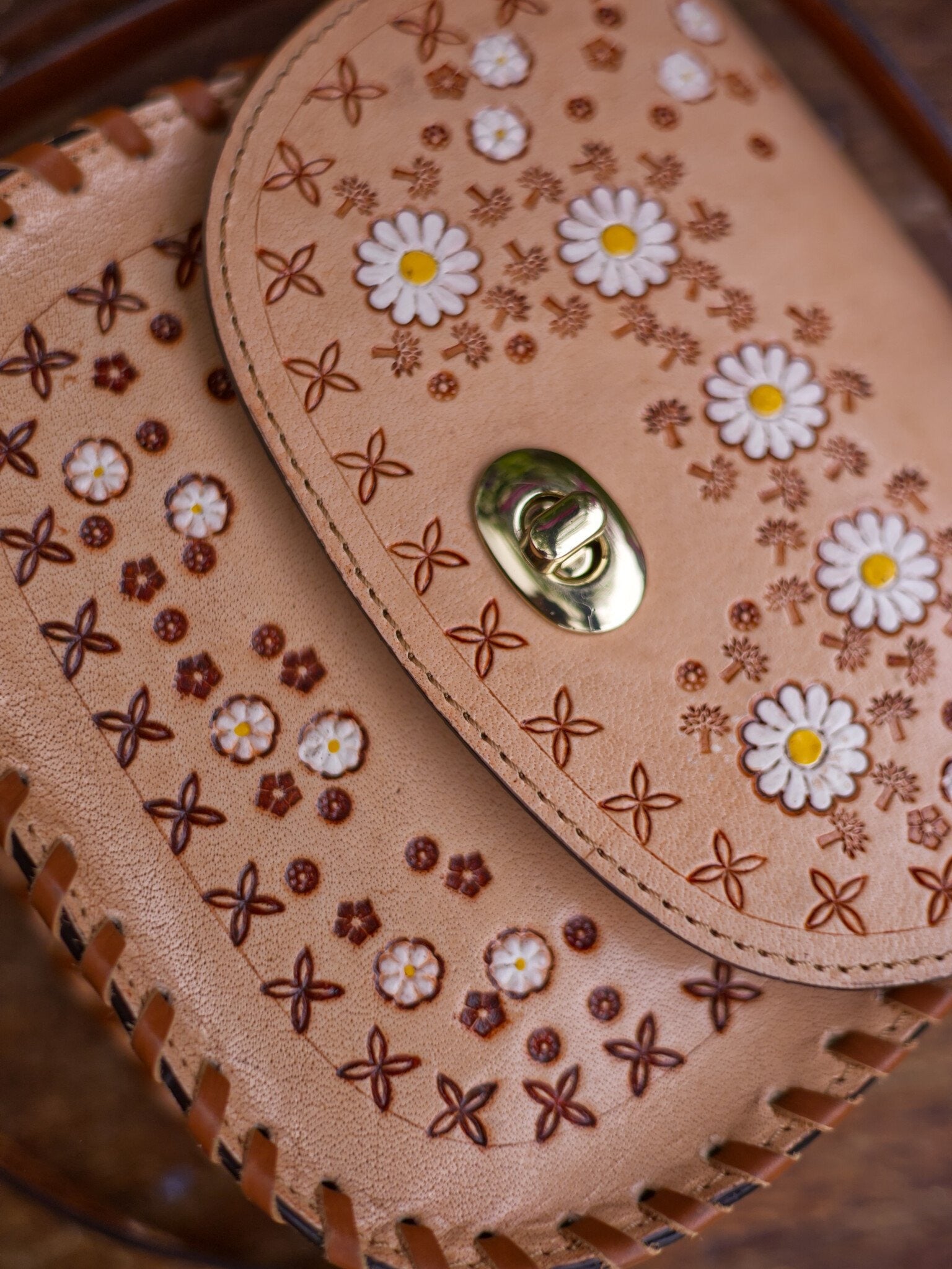 Close-up of a leather handbag with floral patterns and a gold clasp.