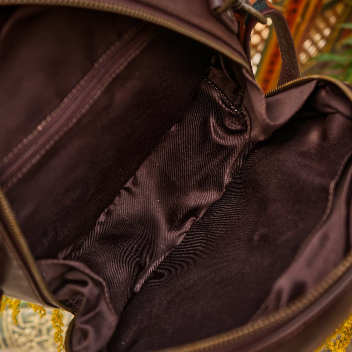 Close-up of a brown leather bag with intricate patterns in the background