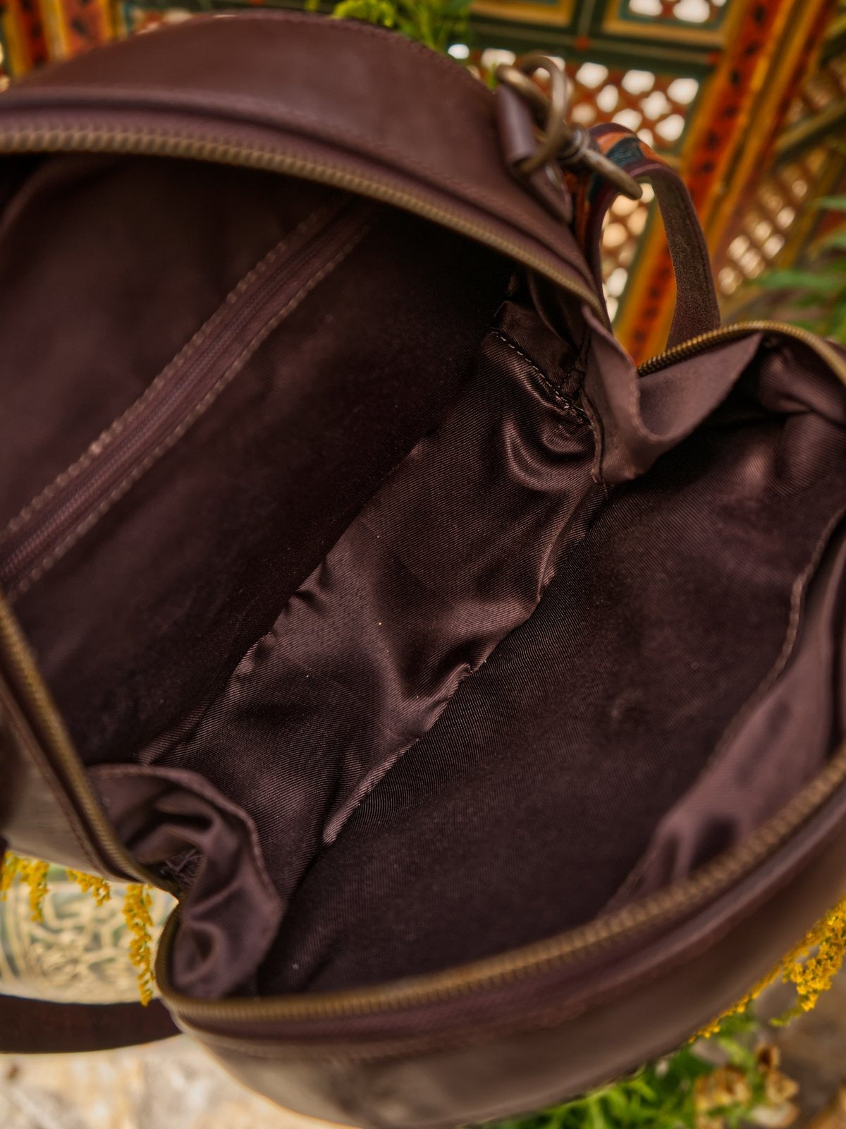 Close-up of a brown leather bag with intricate patterns in the background