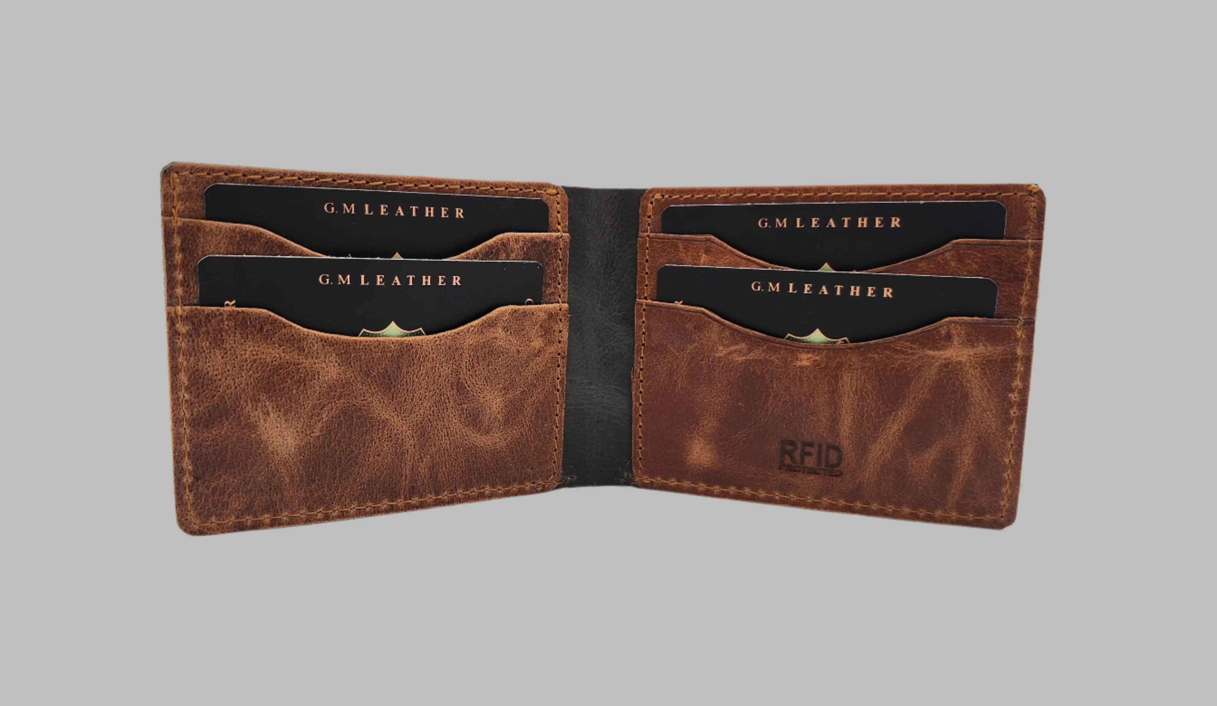 A green and brown leather wallet with upper stitch detailing, displayed in front of its black box packaging with a logo.