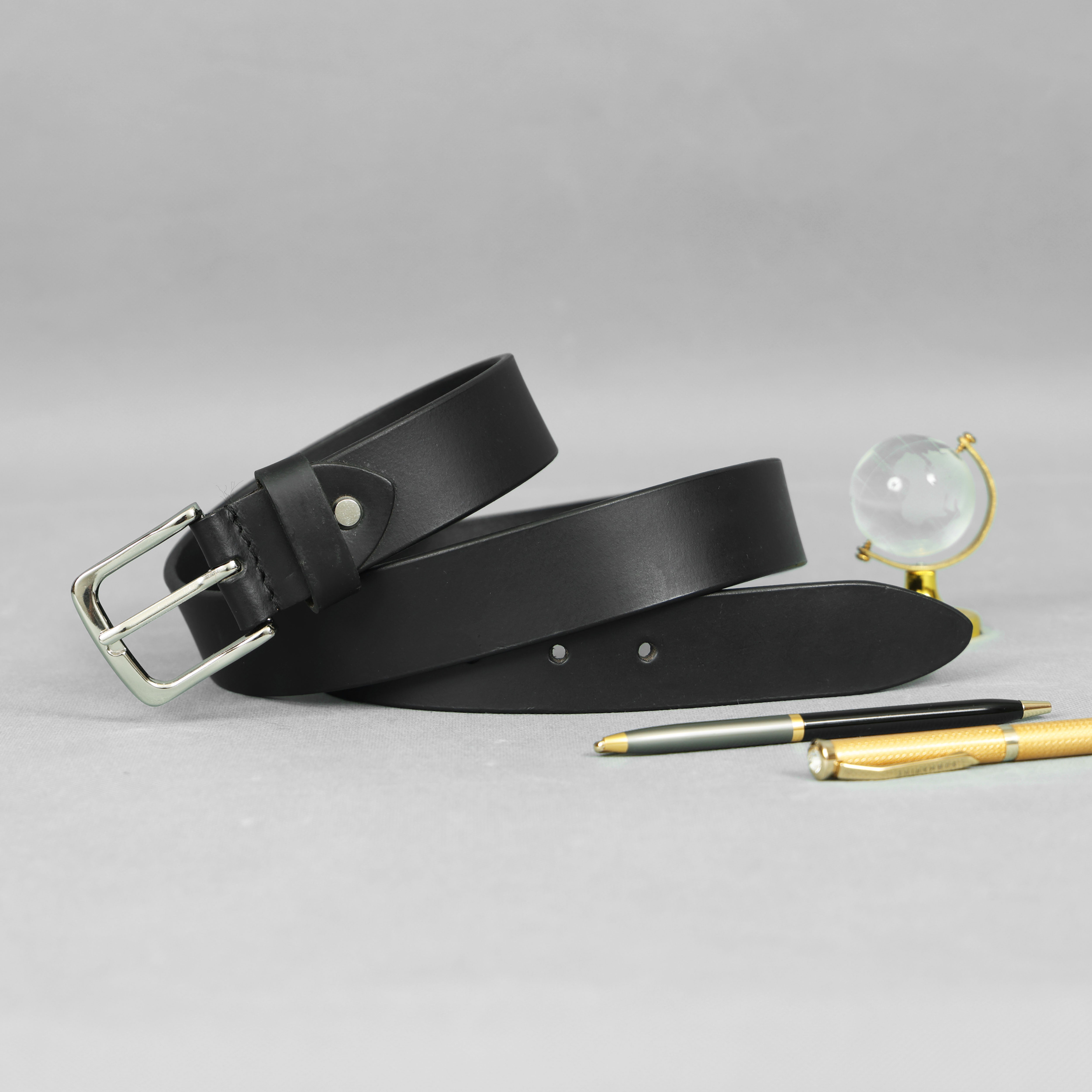 Black leather belt with a pen and magnifying glass on a gray background