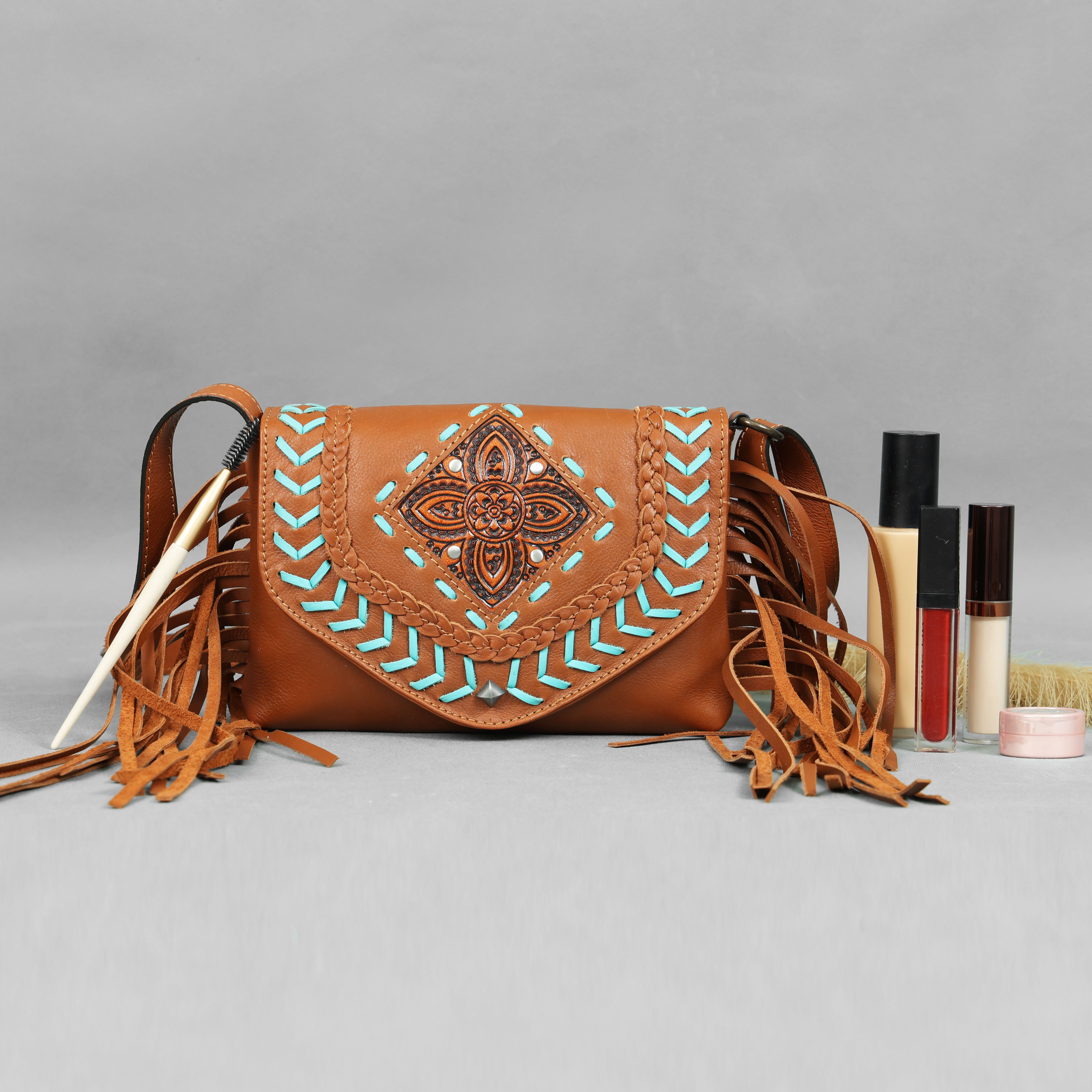 Brown leather handbag with decorative patterns on a gray background