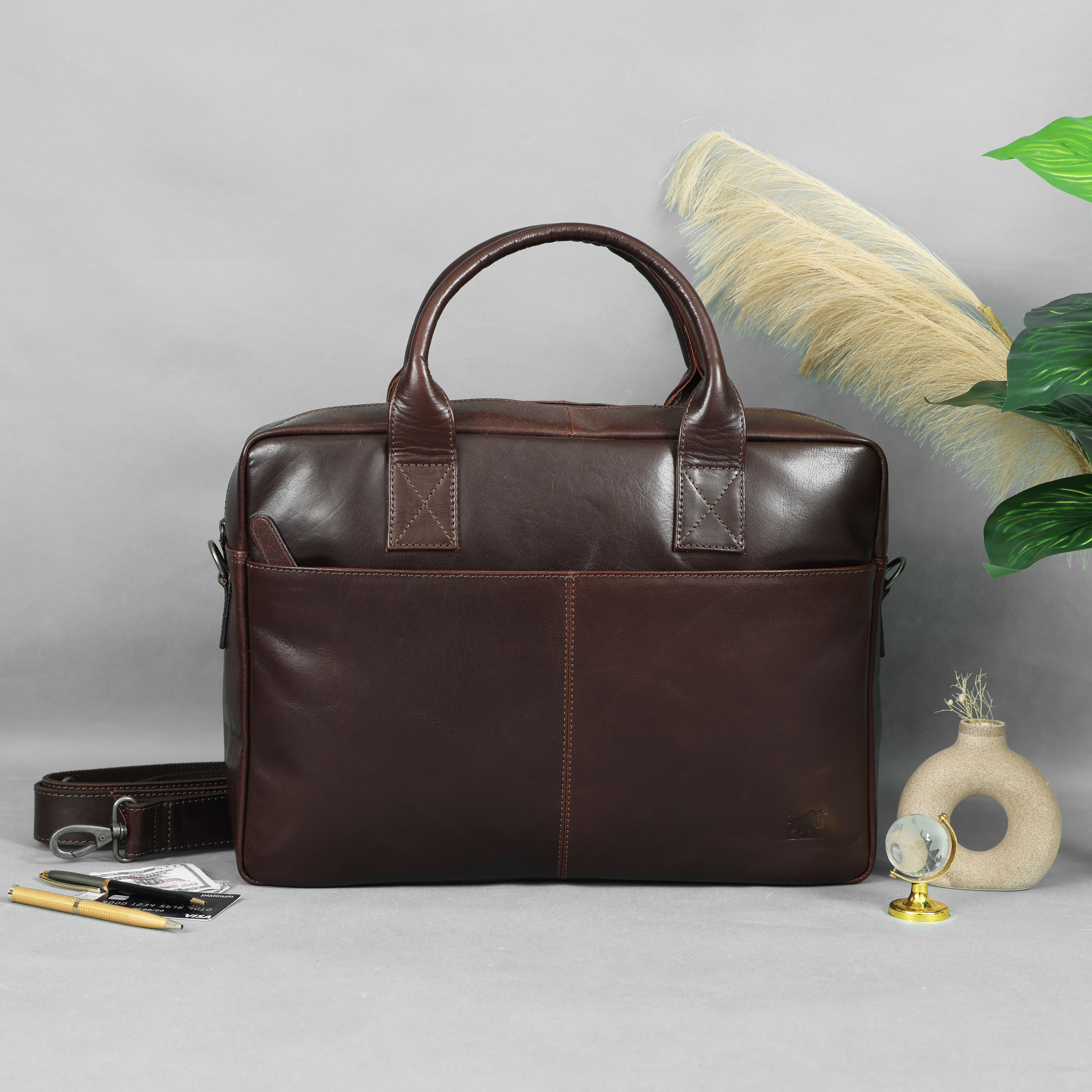 Waxed Dark Brown leather briefcase on a light gray surface with decorative elements.