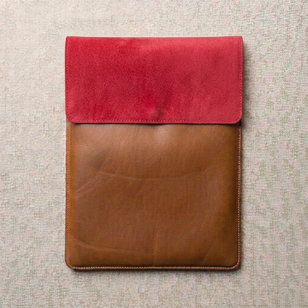 Leather laptop/tablet sleeve featuring a vibrant red suede flap and a brown leather body,