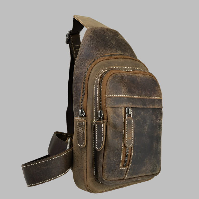 Brown distressed leather sling bag, also known as a chest bag or crossbody backpack, featuring multiple zippered compartments and prominent white stitching.