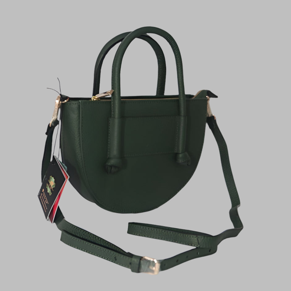 Dark green, half-moon shaped leather crossbody handbag with knotted top handles and a long, adjustable strap on a gray background.
