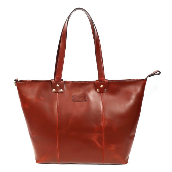 Close-up of a women's premium full-grain leather tote bag in a rich brown/burgundy color with shoulder straps. The bag features visible stitching and is sold by GM Leather Auckland, NZ.