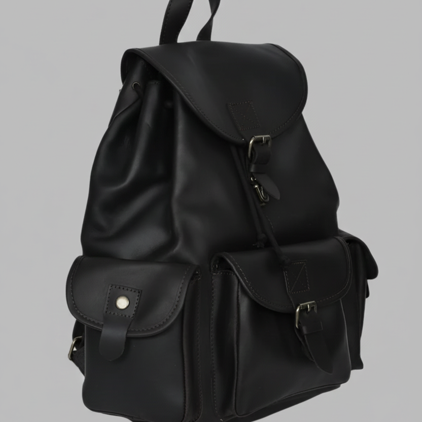A premium GM Leather handcrafted black full grain leather backpack featuring a drawstring closure, multiple buckled pockets, and a top carry handle, available at LynnMall Auckland.