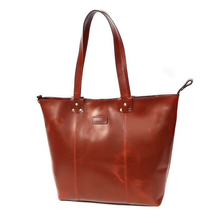 A premium GM Leather handcrafted cognac brown leather tote bag with reinforced shoulder straps and brass rivet accents, available at LynnMall Auckland.