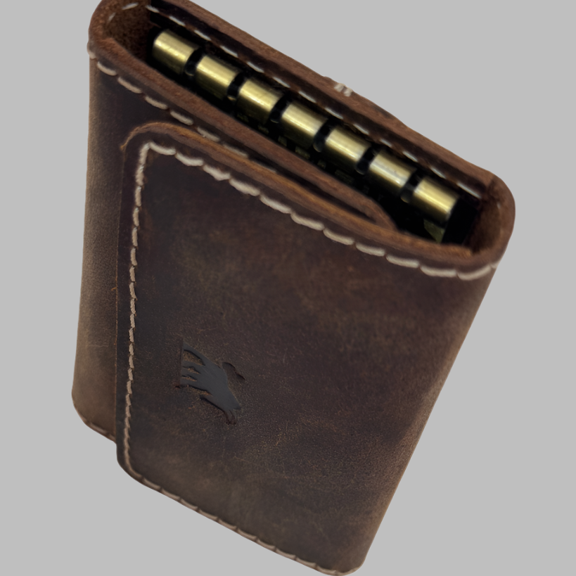 A dark brown, distressed full-grain leather key organiser/case from GM Leather Auckland, opened to show six brass key hooks, keys, and internal card slots holding a fuel card and ID