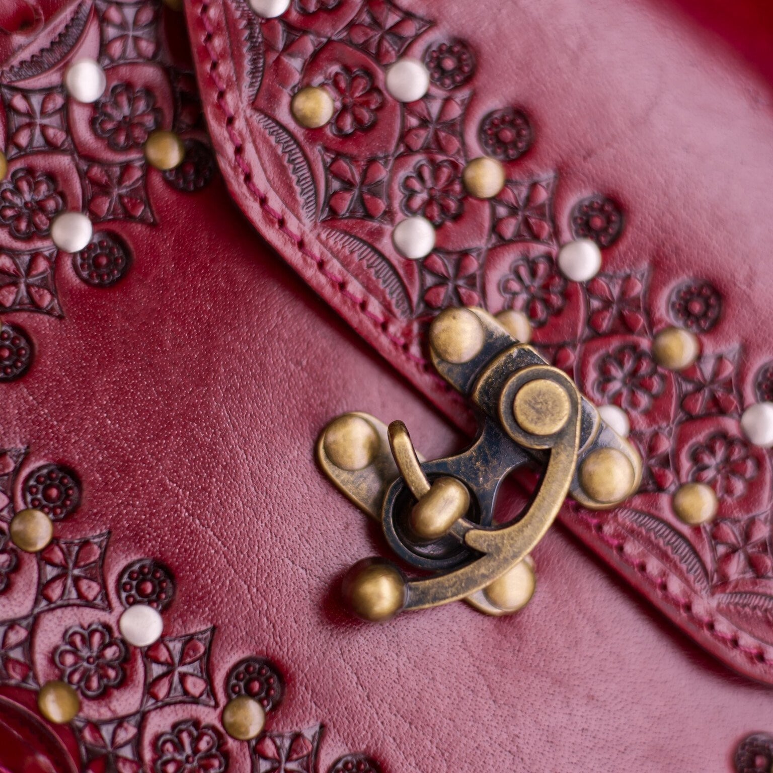 Close-up of a red leather wallet with intricate patterns and a brass clasp.