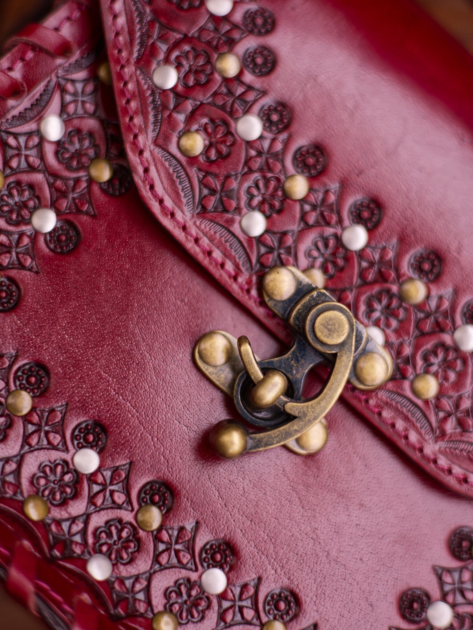 Close-up of a red leather wallet with intricate patterns and a brass clasp.