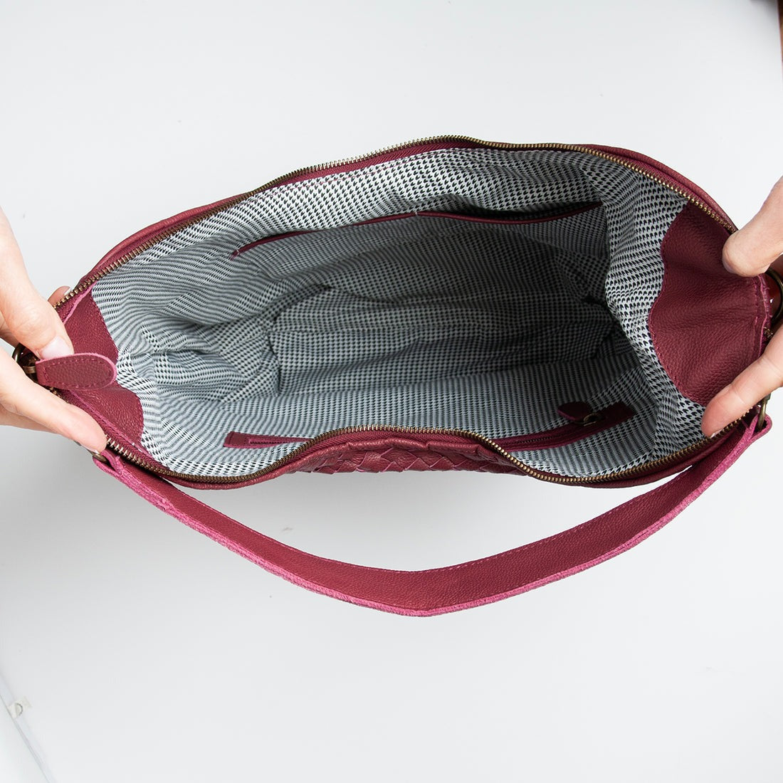 The interior of a GM Leather woven bag featuring a high-quality patterned lining and secure zippered pockets, available at LynnMall Auckland.