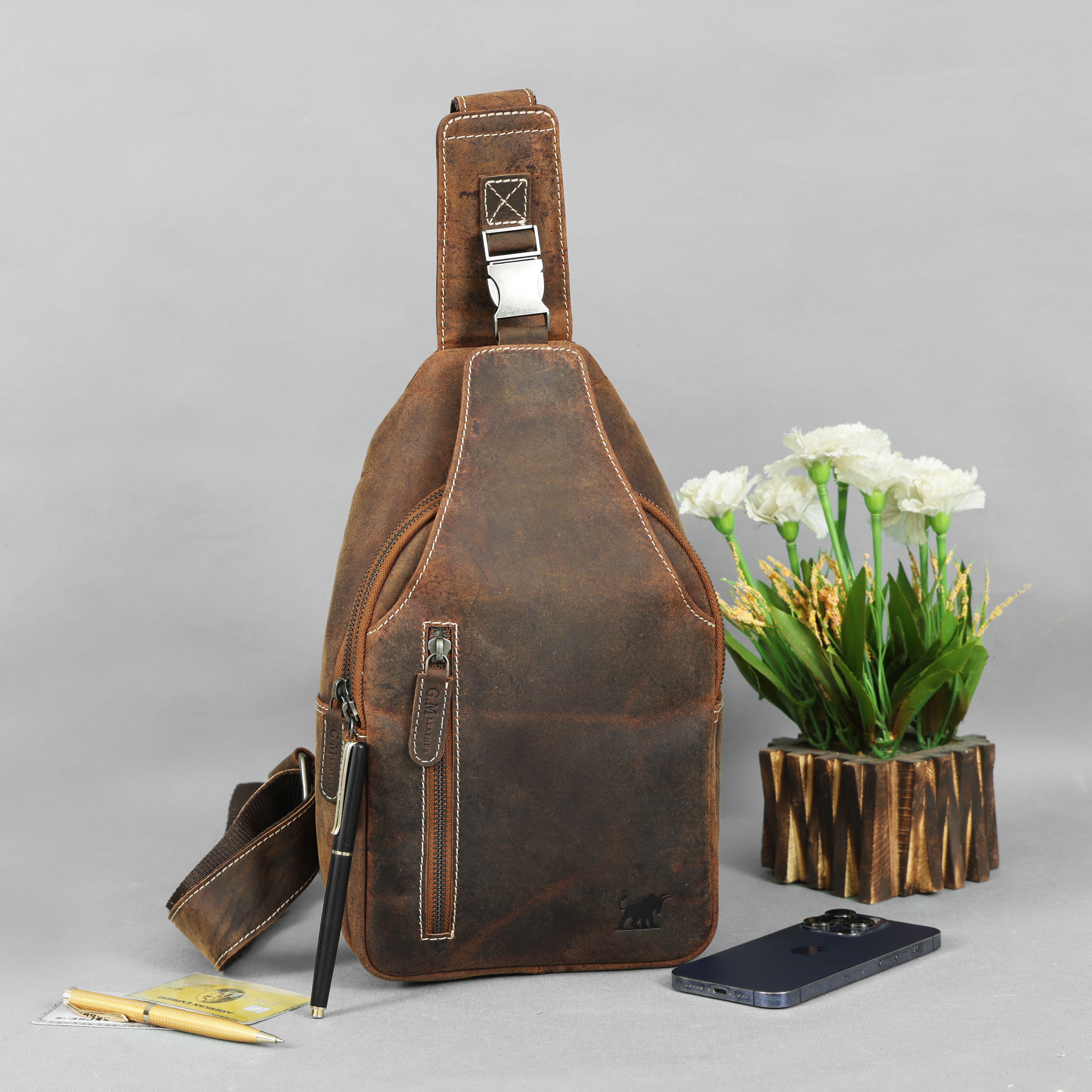 HunterCraft Elite Vintage Leather Crossbody Bag in full-grain distressed brown leather, showing premium stitching, zipper pocket, and compact travel-ready design beside luxury accessories.